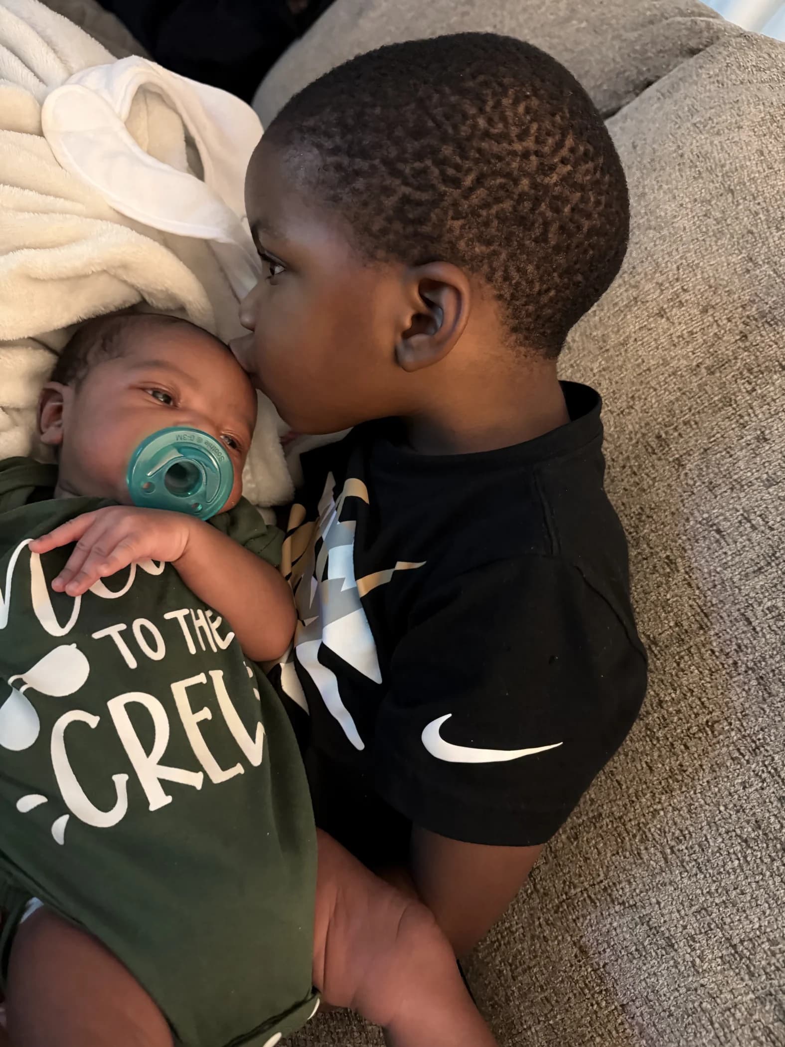 Mykah gently kissing his baby brother Malakai on the forehead