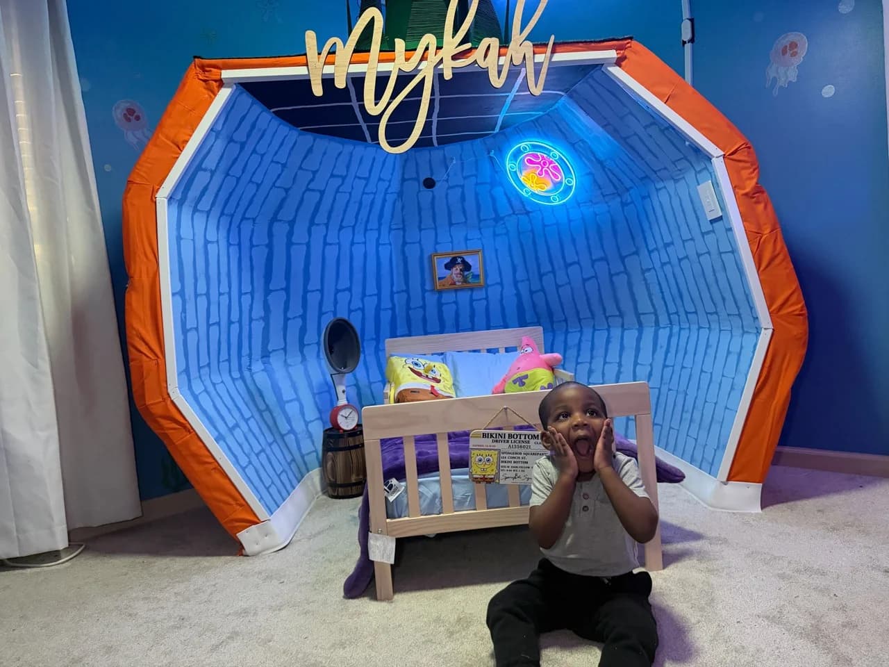 Mykah posing excitedly in front of his finished SpongeBob-inspired pineapple bed surround